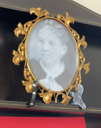 A golden oval frame holds a black-and-white photo of Desdemona Sweet.