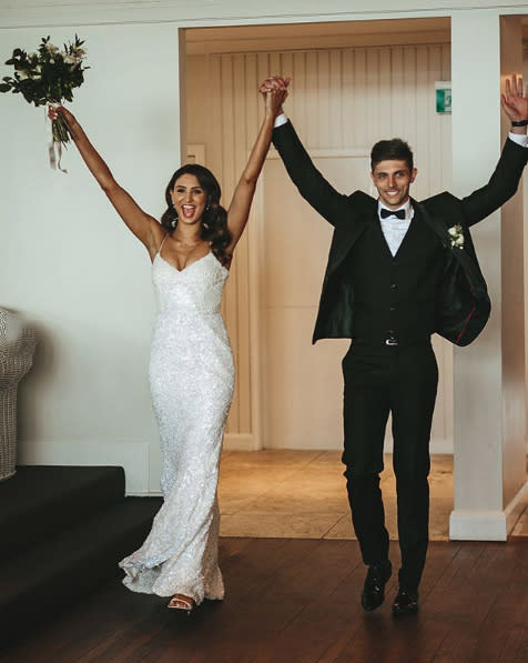 A photo of bride Katie Lolas wearing a wedding dress and her husband on their wedding day.