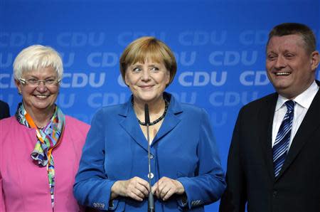 German Chancellor and leader of the Christian Democratic Union (CDU) Angela Merkel smiles (C) as she addresses supporters next to Hermann Groehe (R), CDU secretary general, after first exit polls in the German general election (Bundestagswahl) at party headquarters in Berlin September 22, 2013. REUTERS/Fabrizio Bensch