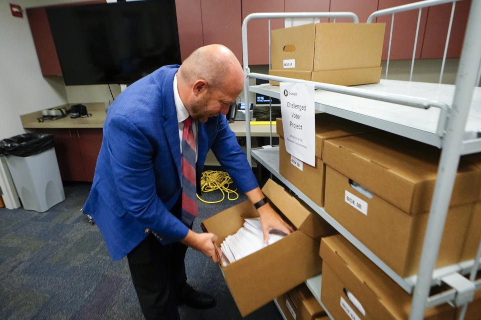 Gwinnett County elections supervisor Zach Manifold looks over boxes of voter challenges on Thursday, Sept. 15, 2022, in Lawrenceville, Ga. Manifold estimated his office has a month to log and research the challenges, before mail ballots go out for the November elections. “It is a tight window to get everything done,” he said. (AP Photo/John Bazemore)