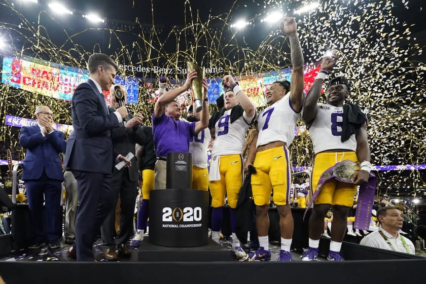 FILE - In this Jan. 13, 2020, file photo, LSU head coach Ed Orgeron holds the trophy after the team's victory over Clemson in an NCAA College Football Playoff national championship game in New Orleans. LSU has begun asking a number of football players to self-quarantine in the past week because of instances in which some players tested positive for COVID-19 after social interactions outside of the Tigers' training facility. (AP Photo/David J. Phillip, File)