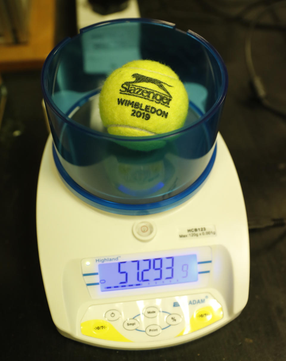 In this photo taken Friday June, 28, 2019, a Wimbledon 2019 tennis ball is weighed at the International Tennis Federation (ITF) lab in Roehampton, near Wimbledon south west London. Based for about 20 years in a three-room area on what used to be a pair of squash courts in Roehampton, the ITF tech lab is filled with more than $1 million worth of machines that help make sure rules are followed and parameters are met. (AP Photo/Alastair Grant)