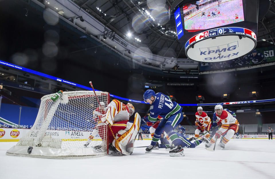 Calgary Flames goalie Jacob Markstrom (25) stops Vancouver Canucks' Elias Pettersson (40) during the first period of an NHL hockey game Saturday, Feb. 13, 2021, in Vancouver, British Columbia. (Darryl Dyck/The Canadian Press via AP)