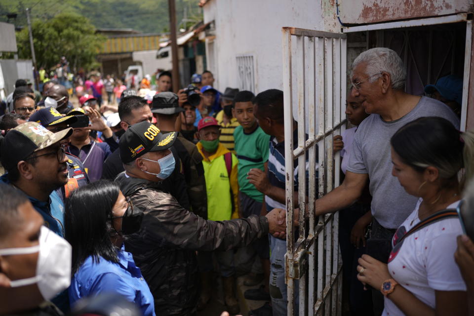 Lawmaker Diosdado Cabello shakes hands with a resident affected by flooding as he and Vice President Delcy Rodriguez, bottom left in blue, visit the area flooded in Las Tejerias, Venezuela, Monday, Oct. 10, 2022. A fatal landslide fueled by flooding and days of torrential rain swept through this town in central Venezuela. (AP Photo/Matias Delacroix)