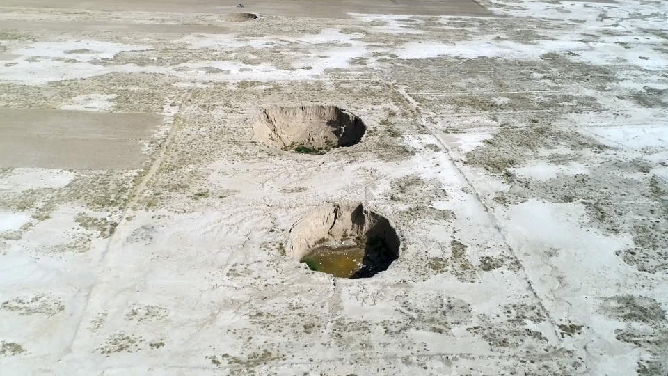 This frame grab from video taken on Aug. 8, 2018, provided by Iranian Students' News Agency, ISNA, shows an aerial view of massive holes caused by drought and excessive water pumping in Kabudarahang, in Hamadan province, western Iran. Some sinkholes formed in western Iran are as deep as 60 meters (196 feet). Already, the drought and water crisis has fed into the sporadic unrest Iran has faced over the last year. (ISNA via AP)