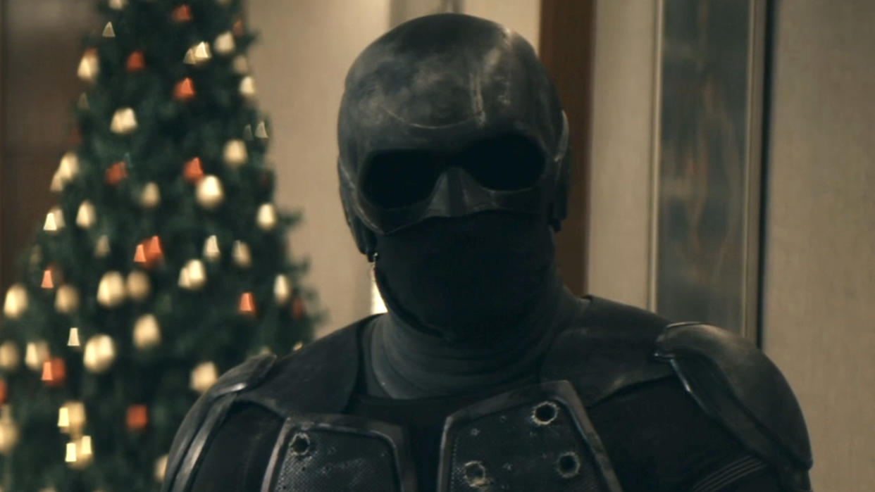  Black Noir standing in front of a Christmas Tree inside Vought building in The Boys Season 4. 