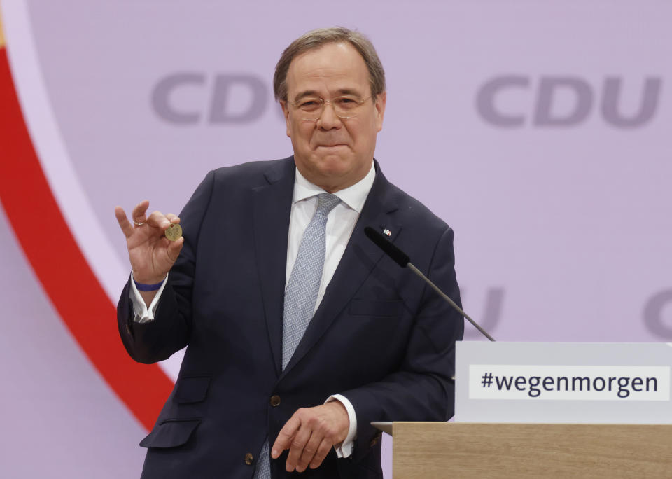 North Rhine-Westphalia's Governor and candidate as leader of the Christian Democratic Union (CDU) Armin Laschet shows a luck coin offered to him by his father as he delivers his speech on the second day of the party's 33rd congress held online because of the coronavirus pandemic, in Berlin on January 16, 2021. German Chancellor Angela Merkel’s party is choosing a new leader on Saturday, eight months before voters decide who will succeed Merkel in a national election. (Odd Andersen/Pool via AP)