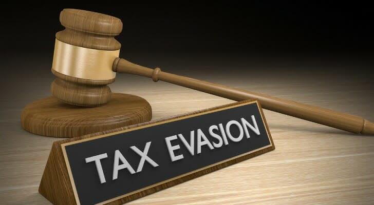 "TAX EVASION" sign on a desktop with a gavel in the background