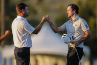 Nick Taylor, right, of Canada, bumps fists with Keith Mitchell as they finished the second round of the Sony Open golf tournament Friday, Jan. 15, 2021, at Waialae Country Club in Honolulu. (AP Photo/Jamm Aquino)