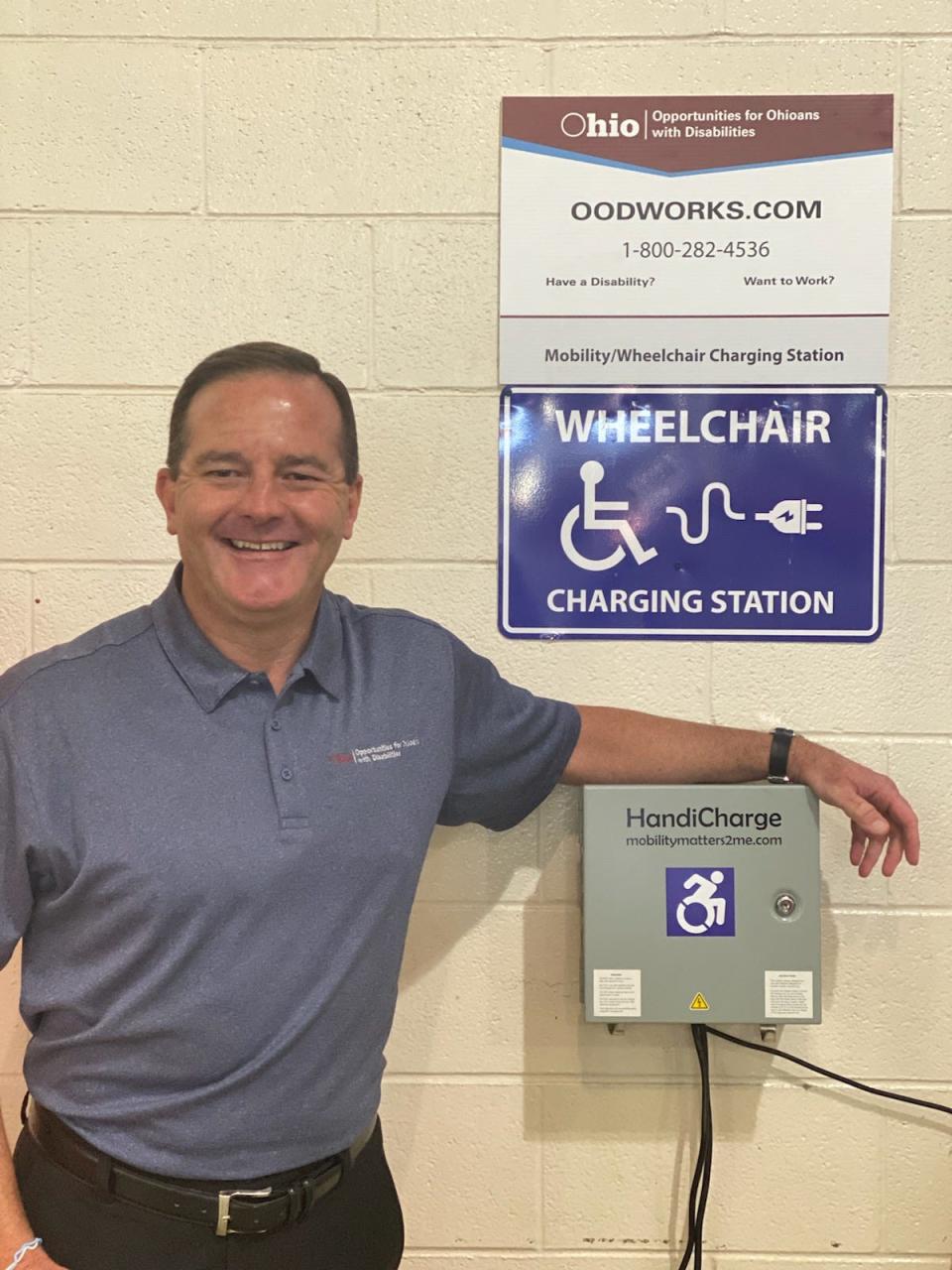 Kevin L. Miller, director of Opportunities for Ohioans with Disabilities, standing next to a wheelchair charging station at the 2023 Ohio State Fair.