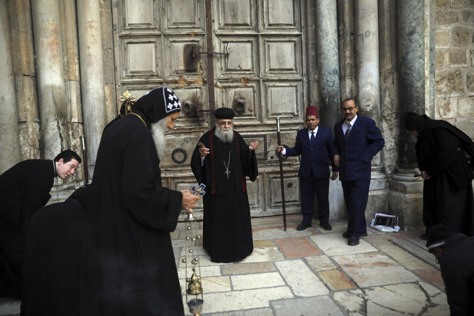 Coptic orthodox priests hold a mass outside closed Church of the Holy Sepulchre, where Christians believe Jesus Christ was buried, in Jerusalem, Saturday, March 28, 2020, as Israel tightens measures to fight the spread of the coronavirus. (AP Photo/Mahmoud Illean)