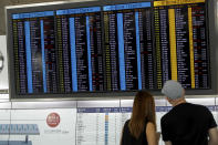 Travellers check on information of their flight at the airport in Hong Kong, Wednesday, Aug. 14, 2019. Flight operations resumed at the airport Wednesday morning after two days of disruptions marked by outbursts of violence highlighting the hardening positions of pro-democracy protesters and the authorities in the Chinese city that's a major international travel hub. (AP Photo/Vincent Thian)