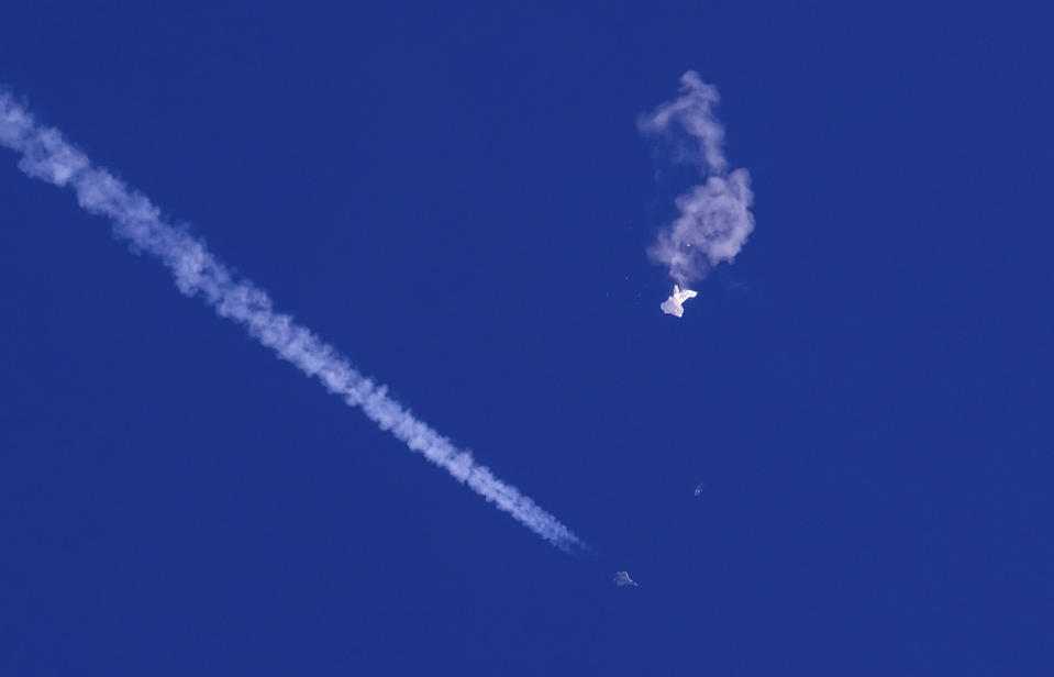 FILE - A fighter jet flies near the remnants of a large balloon after it was struck by a missile over the Atlantic Ocean, just off the coast of South Carolina near Myrtle Beach, Saturday, Feb. 4, 2023. Perhaps no other term than spy balloon this year defined the growing wariness between the world's two largest economies. China rejected allegations of surveillance and insisted that balloon and others were purely for civilian purposes. (Chad Fish via AP, File)