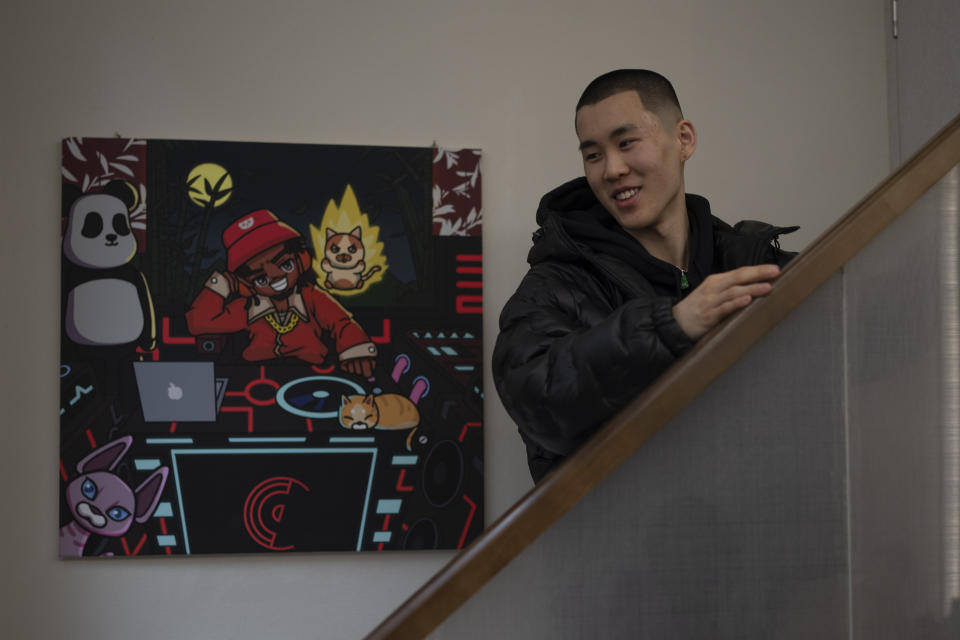 Chinese rapper Haysen Cheng reacts near a painting depicting a rapper at this studio in Chengdu in southwestern China's Sichuan province, Saturday, March 16, 2024. Cheng, a 24 -year old rapper moved to the city from Hong Kong in 2021 to work on his music at the invitation of Harikiri, a British producer who has helped shape the scene and worked with Chengdu's biggest acts in creating music. (AP Photo/Ng Han Guan)
