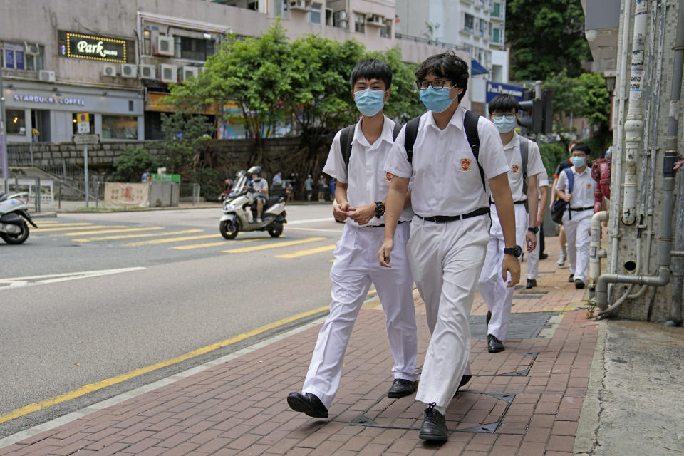 Students wearing face masks to prevent the spread of coronavirus, walk down a street in Hong Kong, Thursday, June 10, 2021. Government officials said Thursday that they will expand the vaccination drive to about 240,000 children from 12 to 15 years old starting Friday, joining other countries such as Singapore and the U.S. that have started vaccinating children. (AP Photo/Kin Cheung)