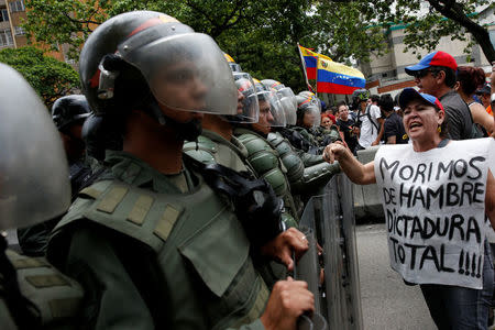 An opposition supporter carrying a sign that reads "We starve. Total dictatorship" shouts at Venezuelan National Guards during clashes at a rally to demand a referendum to remove President Nicolas Maduro in Caracas, Venezuela, May 18, 2016. REUTERS/Carlos Garcia Rawlins