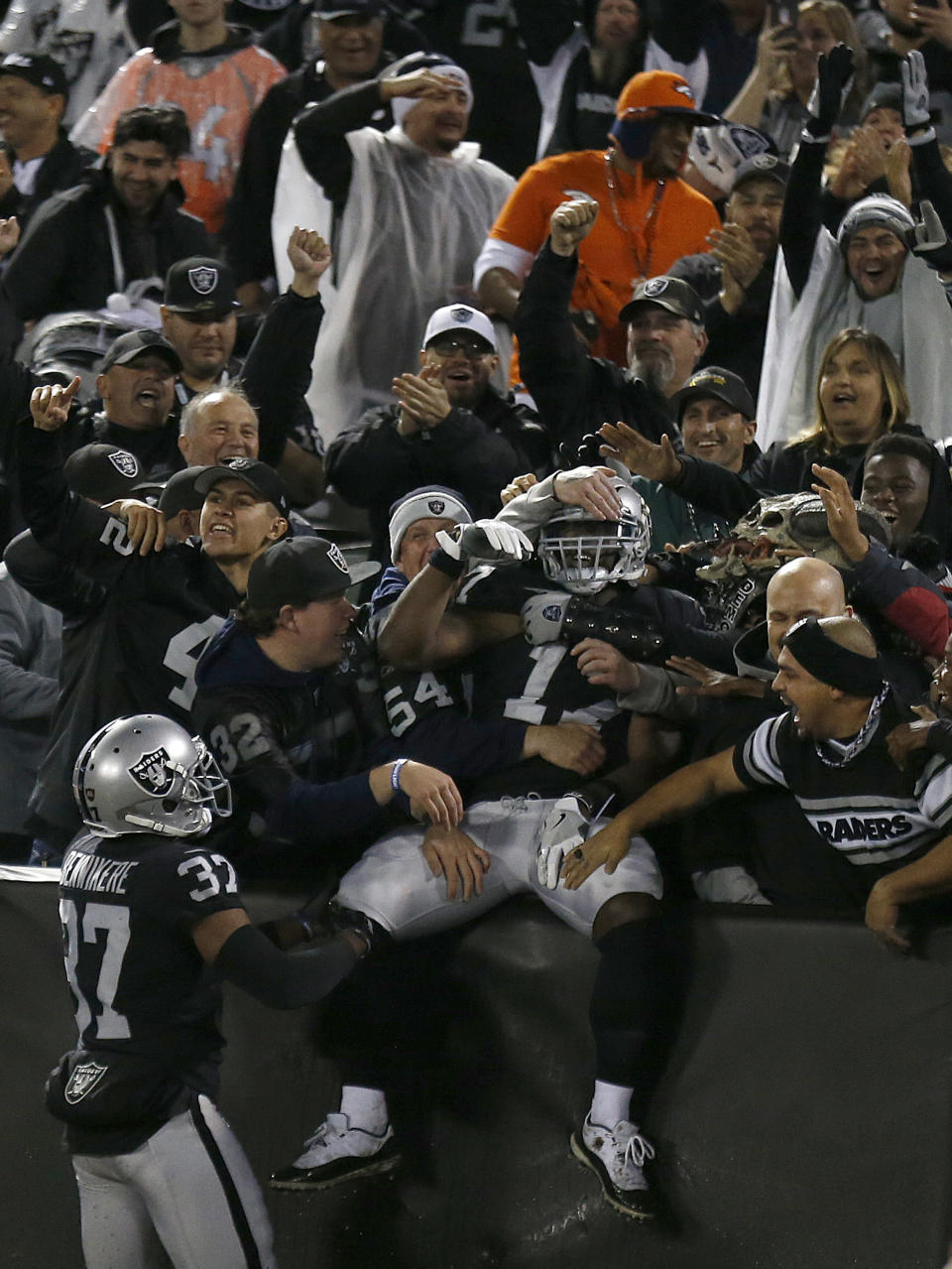 Oakland Raiders' Dwayne Harris, center, celebrates with fans after returning a punt for a touchdown against the Denver Broncos during the first half of an NFL football game in Oakland, Calif., Monday, Dec. 24, 2018. (AP Photo/D. Ross Cameron)