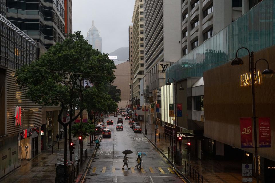 People shelter from the rain with umbrellas while crossing a street as Typhoon Chaba passes Hong Kong on July 2, 2022. (Photo by Bertha WANG / AFP) (Photo by BERTHA WANG/AFP via Getty Images)