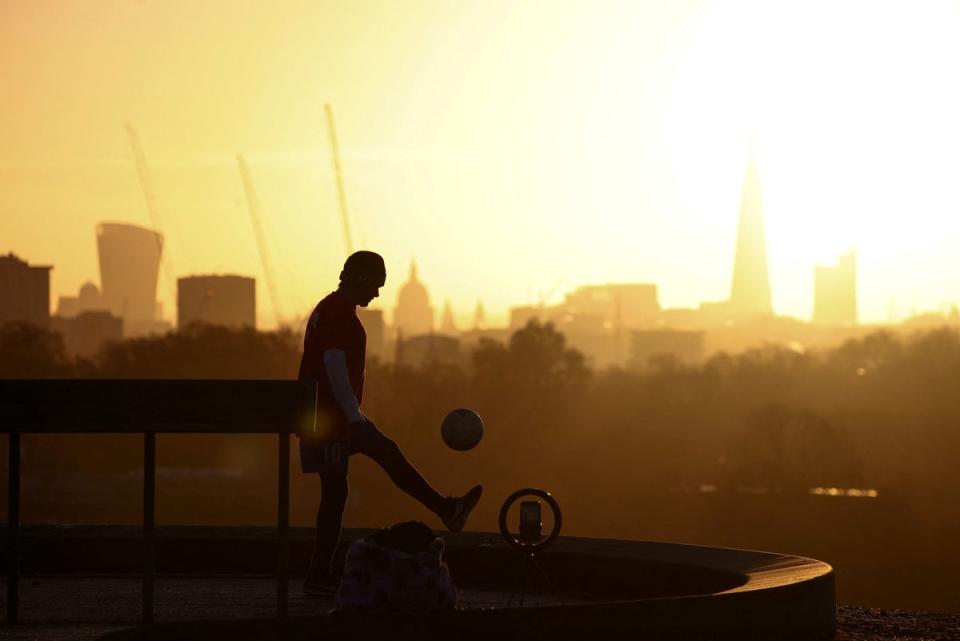 25 November 2022: A person films himself doing kick-ups with a football during sunrise on Primrose Hill in London (Reuters)