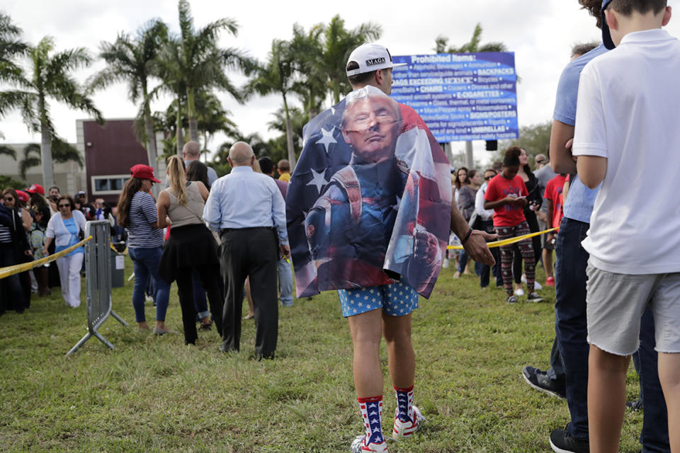 Denis Gomez, of Miami, wears a cape with the face of President Donald Trump as he stands in line outside of Miami's King Jesus International Ministry church where Trump held a rally for evangelical supporters in Jan. 2020.