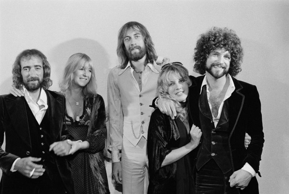 steve nicks and lindsey buckingham smile at the camera embracing each other in this black and white photo