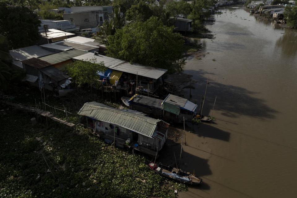 Houseboats float along a river, including Nguyen Thi Thuy's home, front, and her small boat, where she lives with her two grandchildren, in Can Tho, Vietnam, Wednesday, Jan. 17, 2024. Unable to afford rent on land, the small family has lived on a small houseboat ever since. (AP Photo/Jae C. Hong)