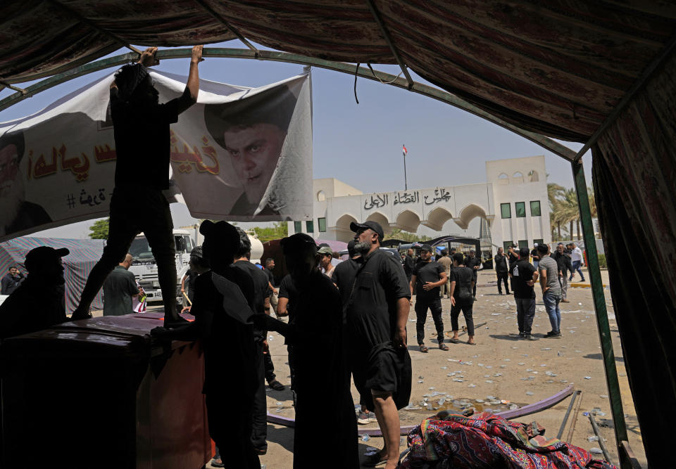 Supporters of Iraqi Shiite cleric Muqtada al-Sadr hang a banner with a picture of him during a protest in front the Supreme Judicial Council, in Baghdad, Iraq, Tuesday, Aug. 23, 2022. Dozens of supporters of al-Sadr, an influential Shiite cleric in Iraq, rallied on Tuesday in Baghdad’s heavily-fortified Green Zone, demanding the dissolution of parliament and early elections. The demonstration underscored how intractable Iraq's latest political crisis has become. (AP Photo/Hadi Mizban)