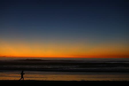 A women jogs along the ocean after sunset in Solana Beach following a record setting day of temperatures according to local media, in Southern California, U.S., October 23, 2017. REUTERS/Mike Blake