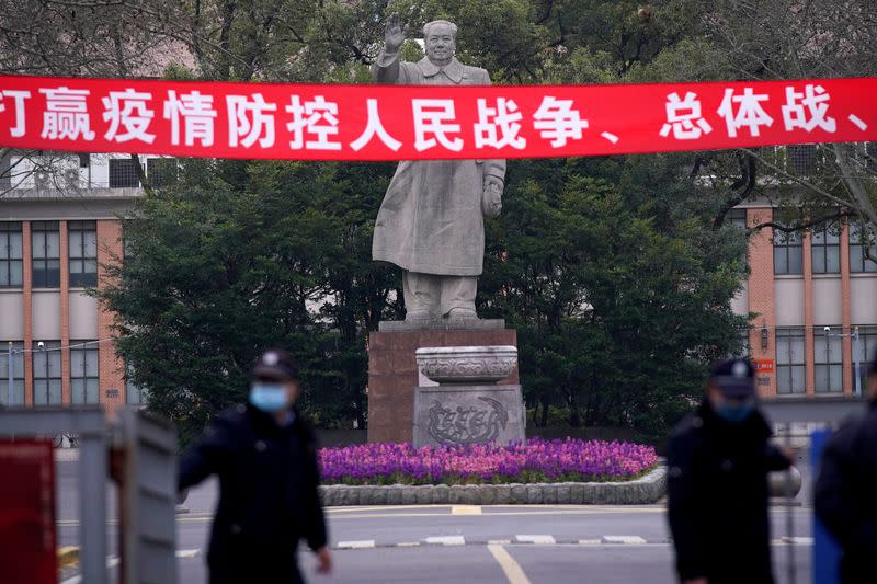 Security guards wearing protective masks are seen in front of a statue of former Chinese leader Mao Zedong at Tongji University as the country is hit by an outbreak of the coronavirus, in Shanghai