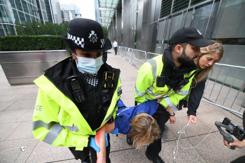 A Met Police officer and a Canary Wharf security guard carry a doctor away by her arms and legs after she refused to move herself (Gareth Morris)