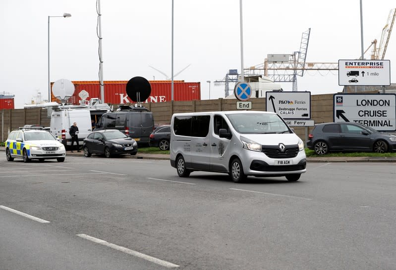A vehicle of a funeral home, escorted by police, leaves the Port of Tilbury where the bodies of immigrants are being held by authorities, following their discovery in a lorry in Essex on Wednesday morning, in Tilbury