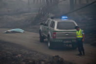 <p>A policeman stands by a dead body of a victim of a wildfire in Pedrogao, on June 18, 2017. At least 62 people have been killed in forest fires in central Portugal, many of them trapped in their cars as flames swept over a road Saturday evening. (Patricia De Melo Moreira/AFP/Getty Images) </p>