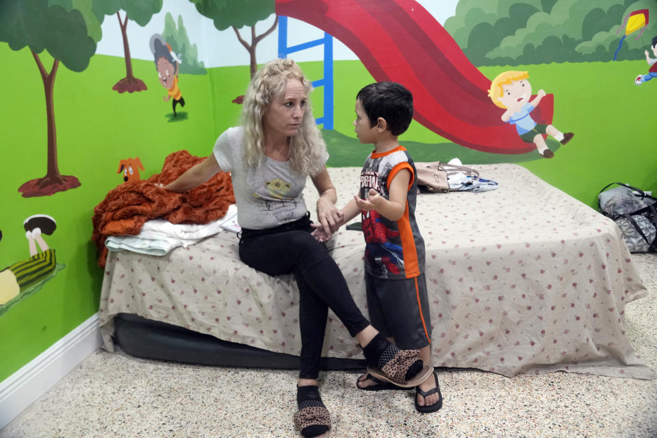 Daneilis Tamayo listens to her son Daniel, 3, in the Iglesia Rescate church school classroom her family uses overnight, Tuesday, Feb. 21, 2023, in Hialeah, Fla. Daneilis arrived in the U.S. with her three children on an overcrowded boat from Cuba. The family wonders the city during the day until they are able to rest in the classrooms in the evening. The church supplies portable showers and toilets. (AP Photo/Marta Lavandier)