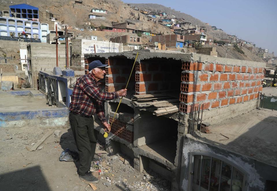 El comerciante retirado Víctor Coba toma medidas de las tumbas que está construyendo para su familia en el cementerio de San Lázaro en las afueras de Lima, Perú, el miércoles 12 de mayo de 2021. El hombre, de 72 años, está construyendo tumbas para él, su esposa y otros cuatro familiares en un espacio estrecho en el cementerio después de enterarse de que dos docenas de sus vecinos murieron de coronavirus. En la temporada más contagiosa y letal de la pandemia, los entierros en la capital peruana se tornan complicados por la falta de espacio en los camposantos. (Foto AP/Martín Mejía)