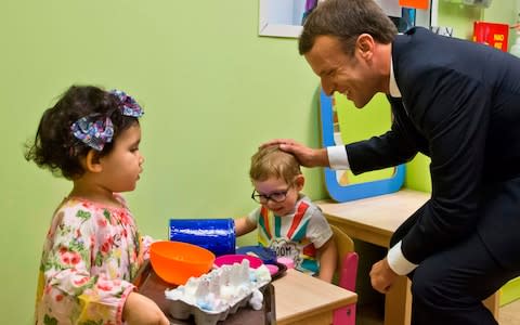 French President Emmanuel Macron (R) visits a nursery school, in Gennevilliers, north of Paris, on October 17, 2017, as part of his action to combat child and youth poverty. - Credit:  MICHEL EULER/AFP