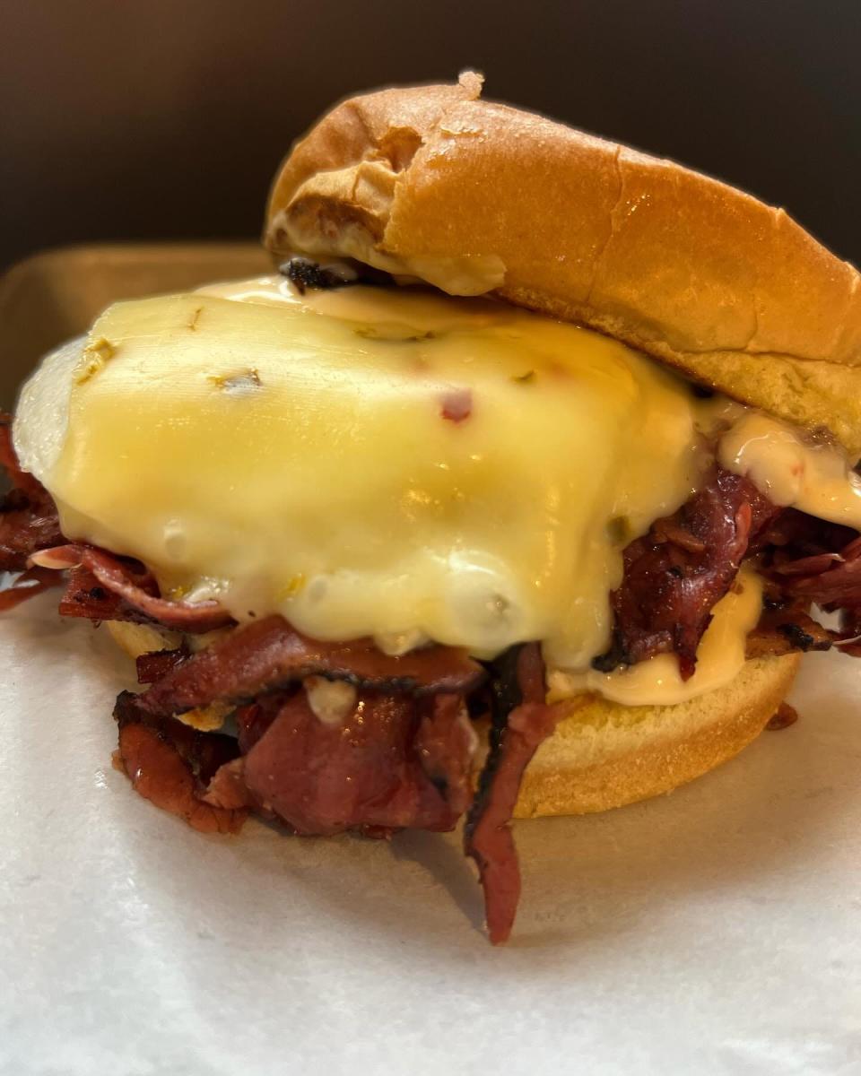 The Wilson features black pastrami, fried egg, hot honey chive mayo, pepperjack cheese on a potato bun.