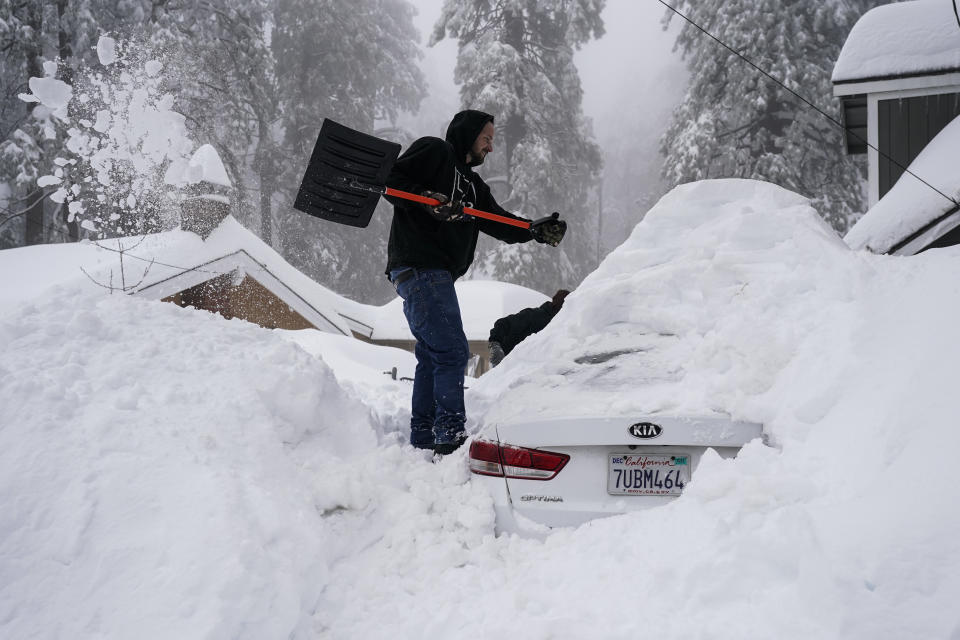 Kenny Rybak, 31, shovels snow around his car in Running Springs, Calif., Tuesday, Feb. 28, 2023. Beleaguered Californians got hit again Tuesday as a new winter storm moved into the already drenched and snow-plastered state, with blizzard warnings blanketing the Sierra Nevada and forecasters warning residents that any travel was dangerous. (AP Photo/Jae C. Hong)