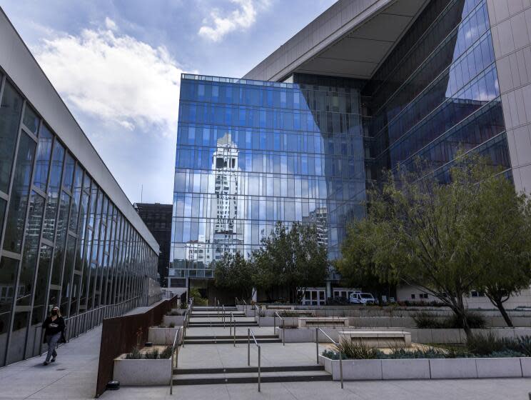 Los Angeles, CA - April 20: Los Angeles City Hall is reflected in the windows of the Los Angeles Police Headquarters on Wednesday, April 20, 2022 in Los Angeles, CA. Los Angeles Mayor Eric Garcetti called Wednesday for an 8.5% increase in the Police Department's operating budget, providing a major boost to overtime pay while also seeking to fill hundreds of vacant positions. Garcetti released his $11.8-billion budget for the coming year, which would increase the LAPD's operating budget by $149 million and take LAPD staffing up to 9,735 police officers by mid-2023, an increase of 29 positions compared with this year's budget. (Allen J. Schaben / Los Angeles Times)