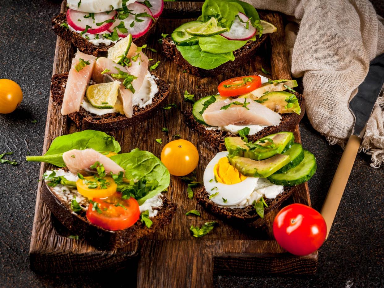 Set of various danish open sandwiches Smorrebrod with fish, egg and fresh vegetables, dark background copy space