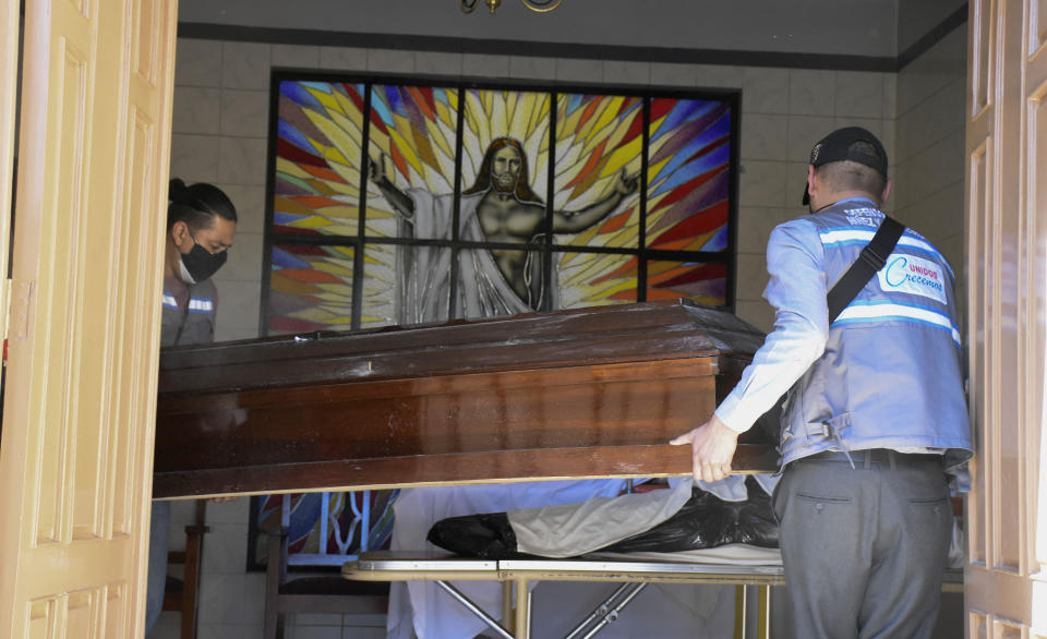 Health workers carry an empty coffin into the San Jose nursing home to recover the body of an recently deceases resident, in Cochabamba, Bolivia, Thursday, July 16, 2020. According to city authorities, 10 elderly people with suspected COVID-19 symptoms have died in the last two weeks at the nursing home. (AP Photo/Dico Solis)