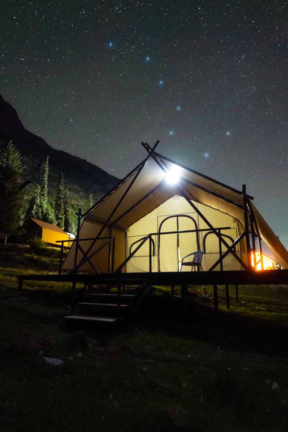 there is a large tent lit from the inside, there are steps leading to the entrance. Above him is a starry sky with a particular pattern of stars known as the Big Dipper shining brightly.