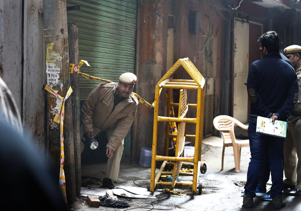 A policeman comes out from the only entrance of an ill-fated building which caught fire on Sunday, in New Delhi, India, Monday, Dec. 9, 2019. Authorities say an electrical short circuit appears to have caused a devastating fire that killed dozens of people in a crowded market area in central New Delhi. Firefighters fought the blaze from 100 yards away because it broke out in one of the area's many alleyways, tangled in electrical wire and too narrow for vehicles to access. (AP Photo/Manish Swarup)