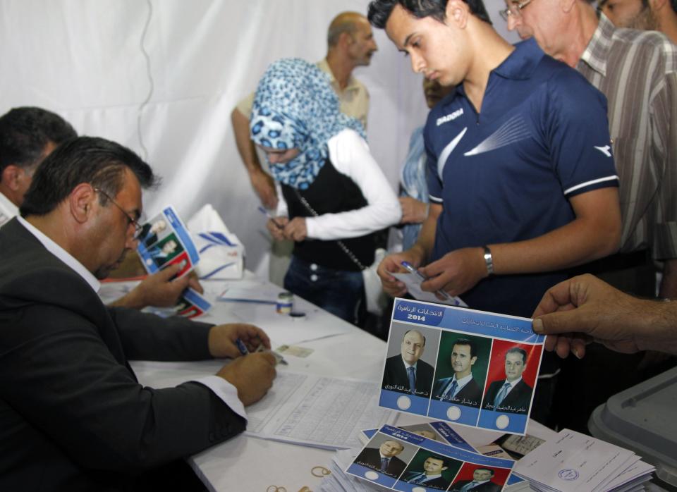 People wait in line to get their ballot papers for the presidential election at a polling centre in Damascus June 3, 2014. Syrians voted on Tuesday in an election expected to deliver an overwhelming victory for President Bashar al-Assad but which his opponents have dismissed as a charade in the midst of Syria's devastating civil war. (REUTERS/Khaled al-Hariri)