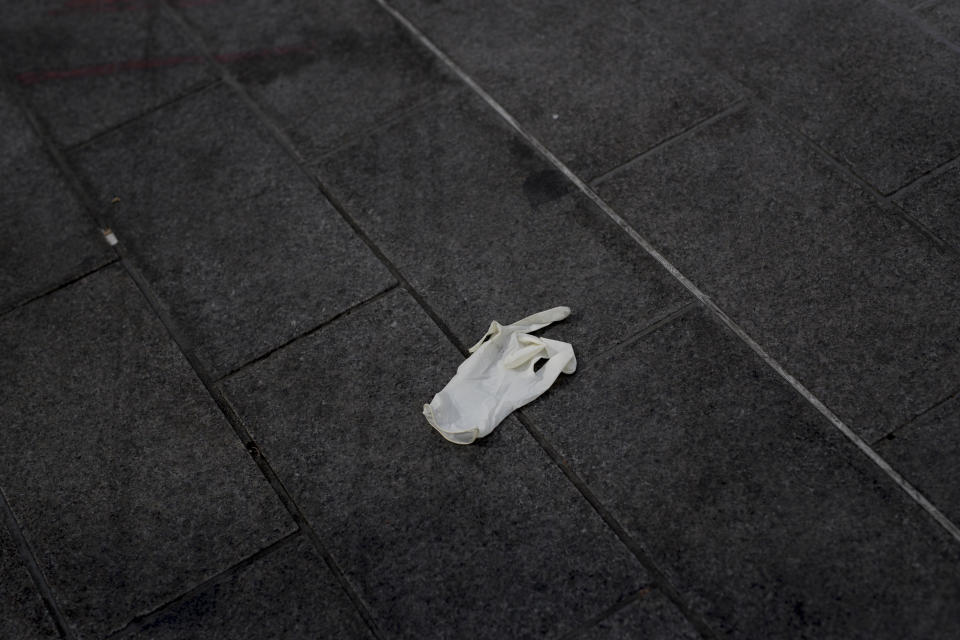 A sanitary glove lies on the pavement of a deserted street just after nationwide confinement measures came into effect, Tuesday, March 17, 2020, in Marseille, southern France. French President Emmanuel Macron announced strong restrictions on freedom of movement in a bid to counter the new coronavirus, as the European Union closed its external borders to foreign travelers. For most people, the new coronavirus causes only mild or moderate symptoms. For some it can cause more severe illness. (AP Photo/Daniel Cole)