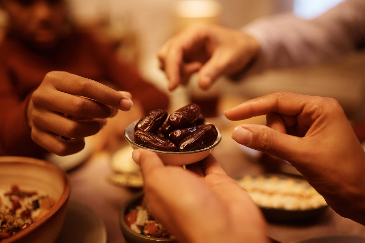 Close up of Muslim family eating dates during Iftar meal at dining table.