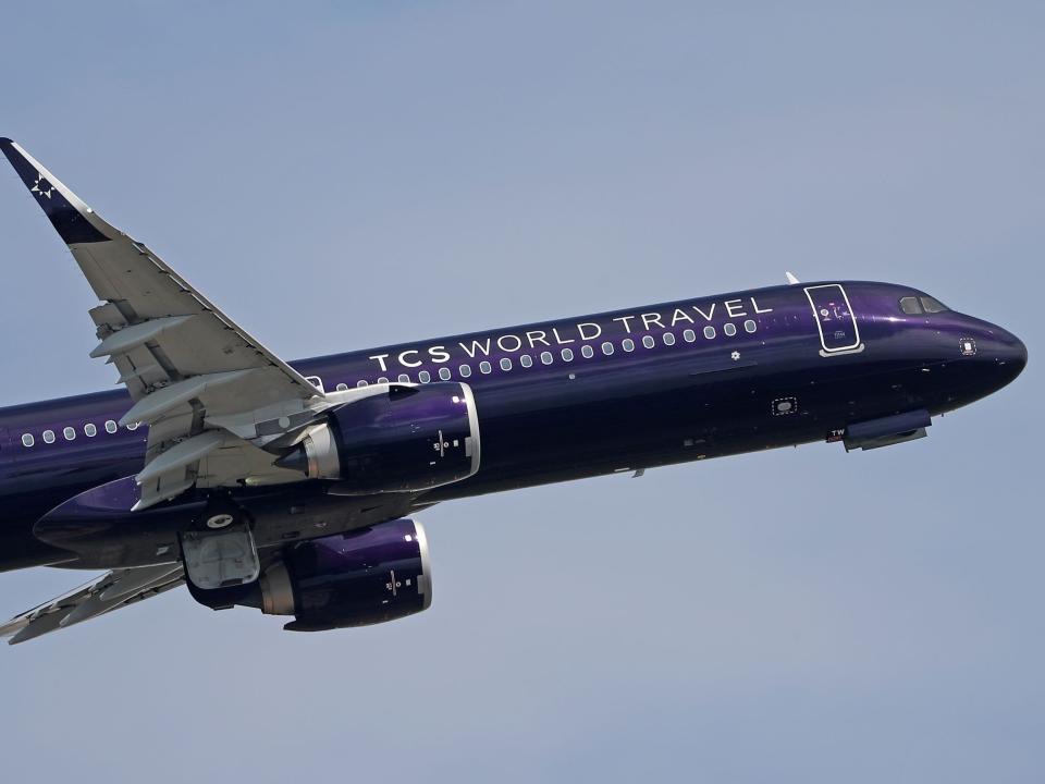 The purple-painted TCS World Travel A321 flying.