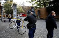 A man moves a bicycle as police officers inspect the site where a stabbing incident happened at an entrance gate of Tokyo University in Tokyo