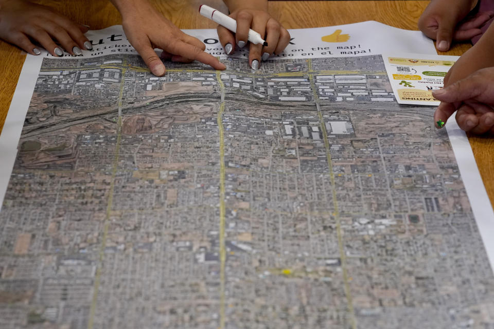 FILE - Residents look at a map of central Phoenix to find locations for a cool corridor at an event hosted by Arizona State University graduate design students at Academia del Pueblo charter school, Friday, Sept 28, 2022, in Phoenix. As heat waves fueled by climate change arrive earlier, grow more intense and last longer, people over 60 who are more vulnerable to high temperatures are increasingly at risk of dying from heat-related causes. (AP Photo/Matt York,File)