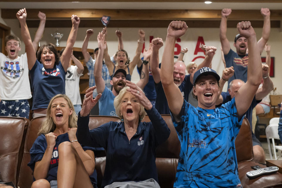 FILE - In this Aug. 4, 2021, file photo, Cousin Haley Crouser, left, grandmother Marie Crouser, center, and brother Matt Crouser, right, watch television coverage in Redmond, Ore., with other family members and friends as Ryan Crouser wins the gold in the men's shot put at the Tokyo Olympics. (AP Photo/Nathan Howard, File)
