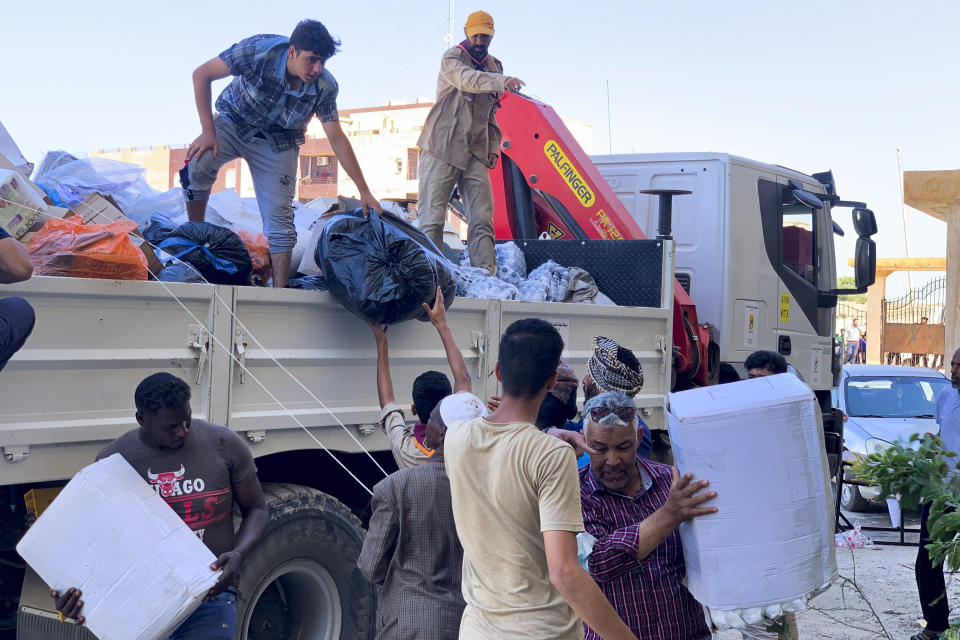 People deliver donated aid to a flash flood-destroyed city of Derna, Libya, Saturday, Sept. 16, 2023. The death toll in Libya's coastal city of Derna has soared to over ten thousand as search efforts continue following a massive flood fed by the breaching of two dams in heavy rains, the Libyan Red Crescent. (AP Photo/Yousef Murad)